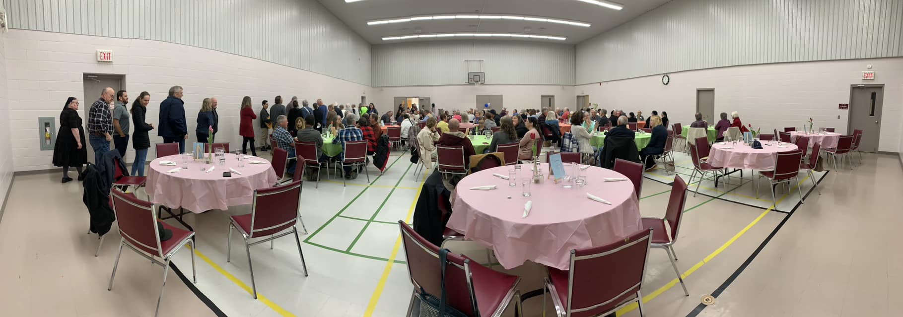 Table and chairs with people attending an event in a gym