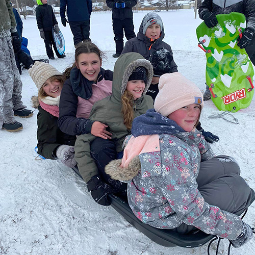Group of girls sitting on a sled outside in winter
